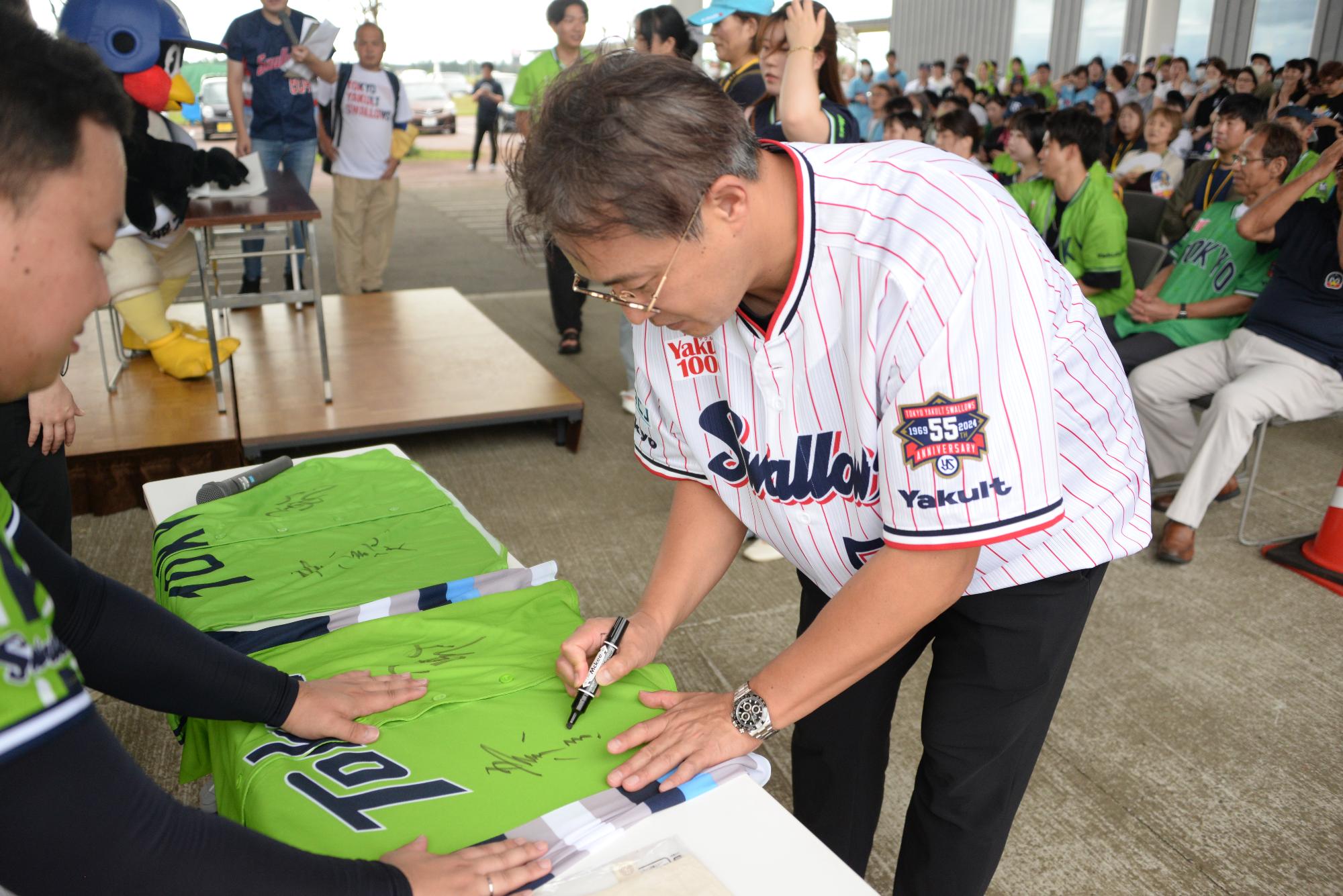 ユニフォームにサインする五十嵐亮太さんの写真
