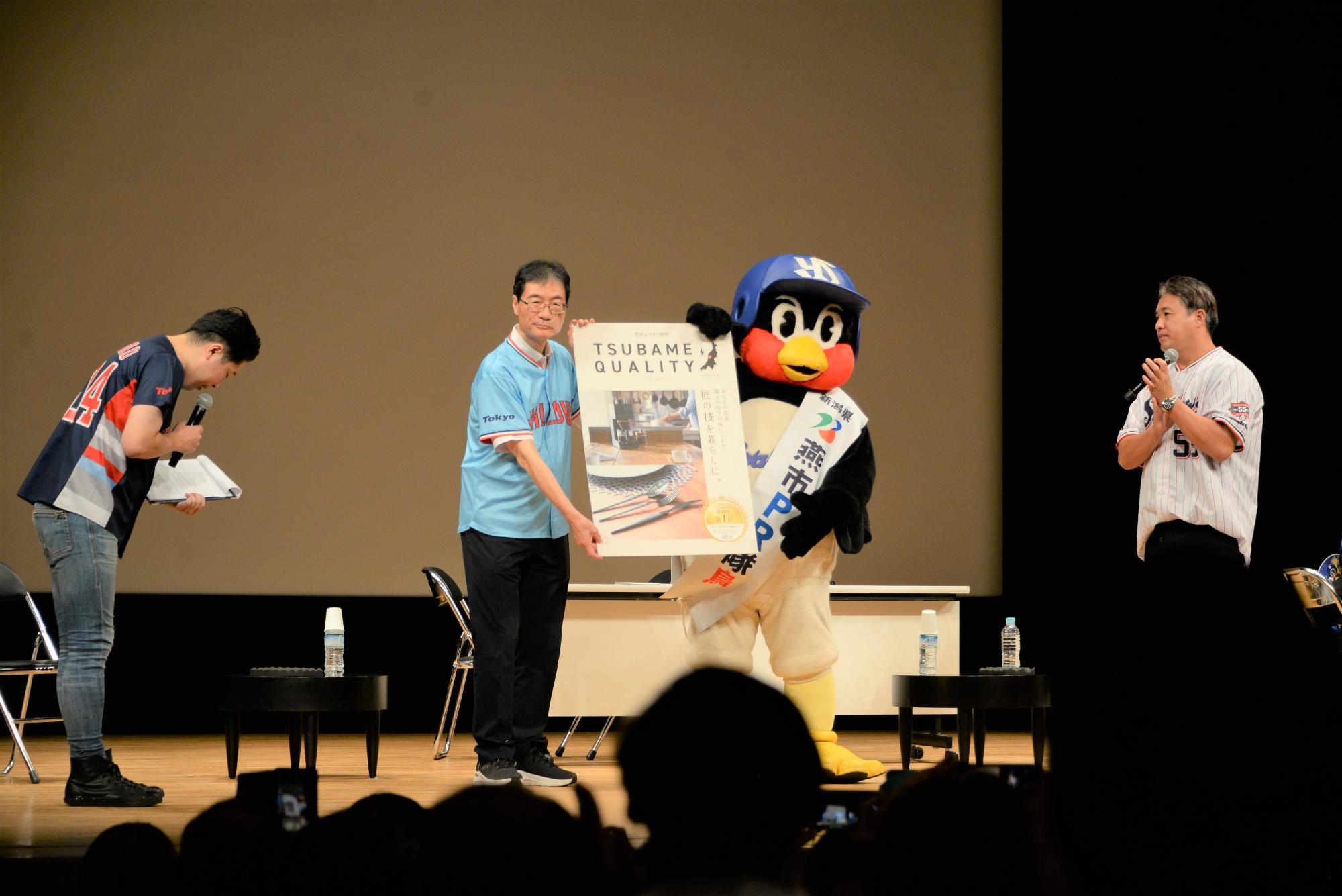 記念品のパネルを持った燕市長とつば九郎の写真