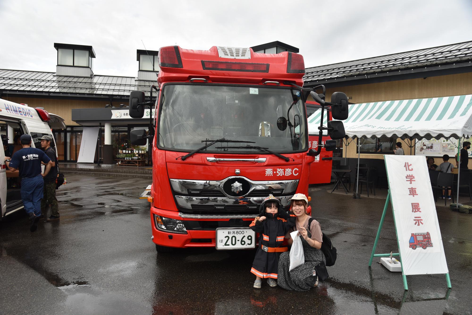 消防車の前でポーズを決める子どもとお母さん