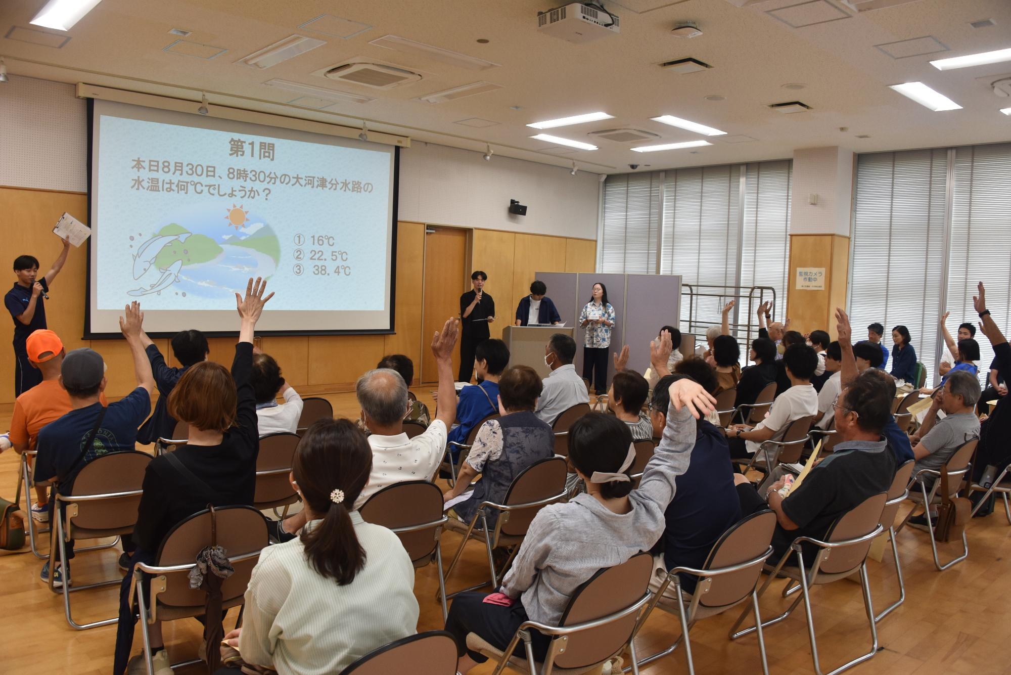 川に関するクイズを出す大学生とクイズに答える来場者