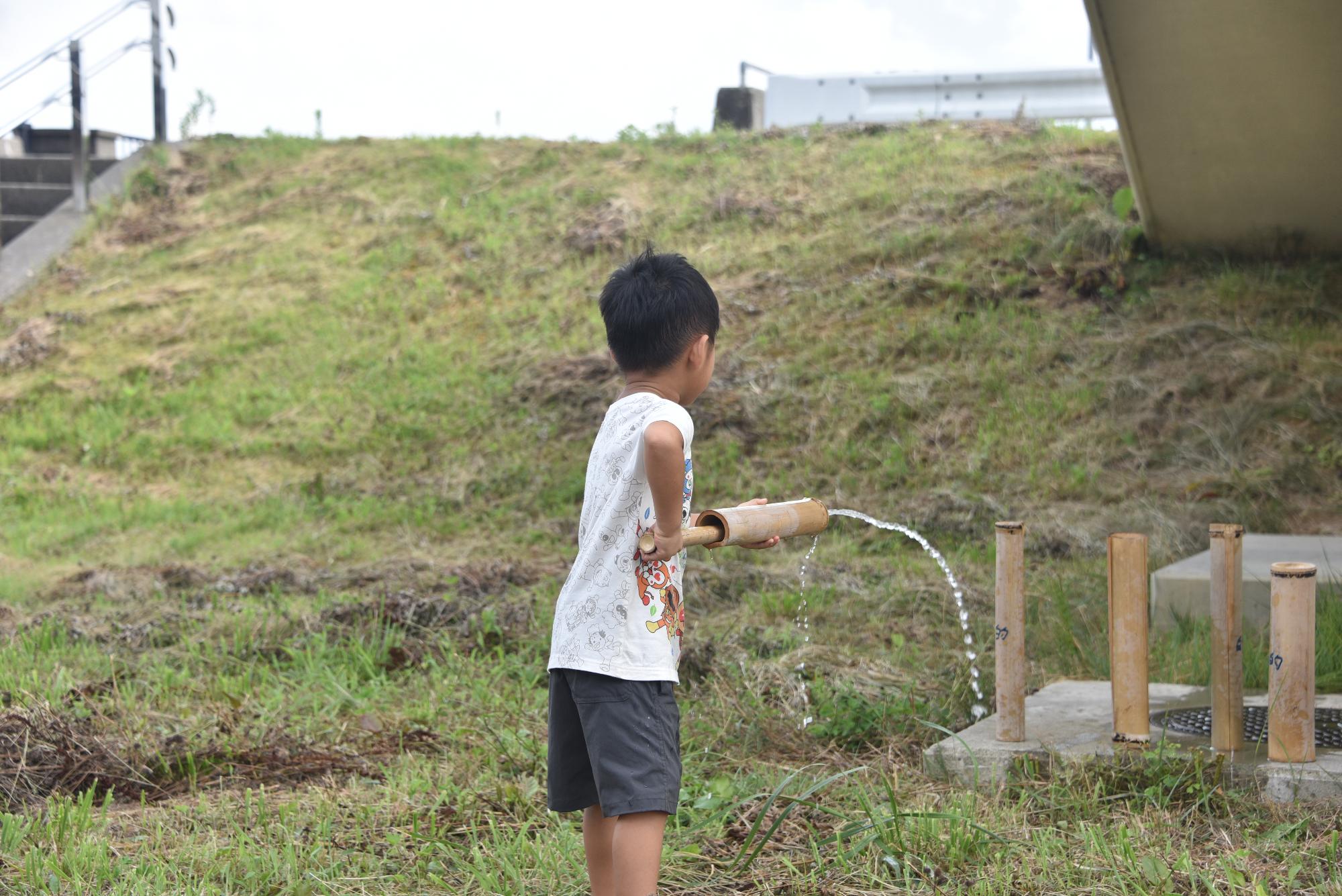 作った水鉄砲で遊ぶこども