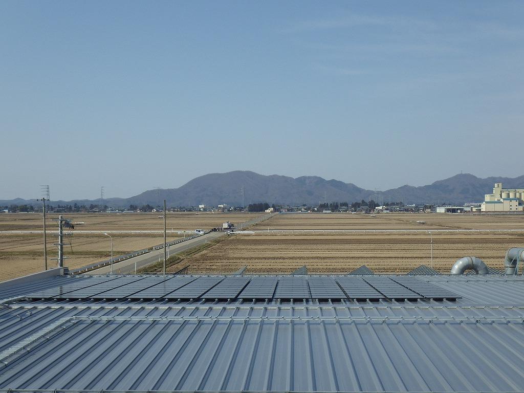 山と田んぼを背景にした太陽電池モジュールの写真