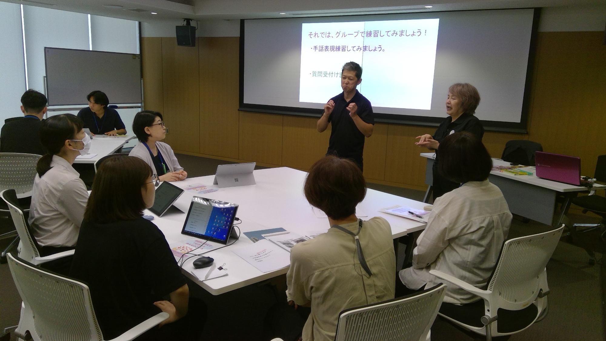 グループで手話を教えてもらっている受講生たちの写真