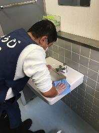 トイレの洗面台を磨く人