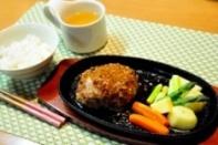 白いご飯とコップに入ったお茶、ハンバーグや野菜などがプレートに盛られている写真
