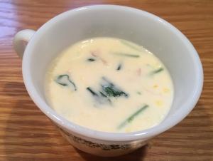 マグカップに、青菜などの具のある白いスープが入っている写真