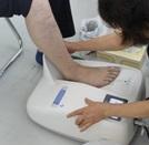 足を機械の上にのせて、骨密度を測っている人の写真