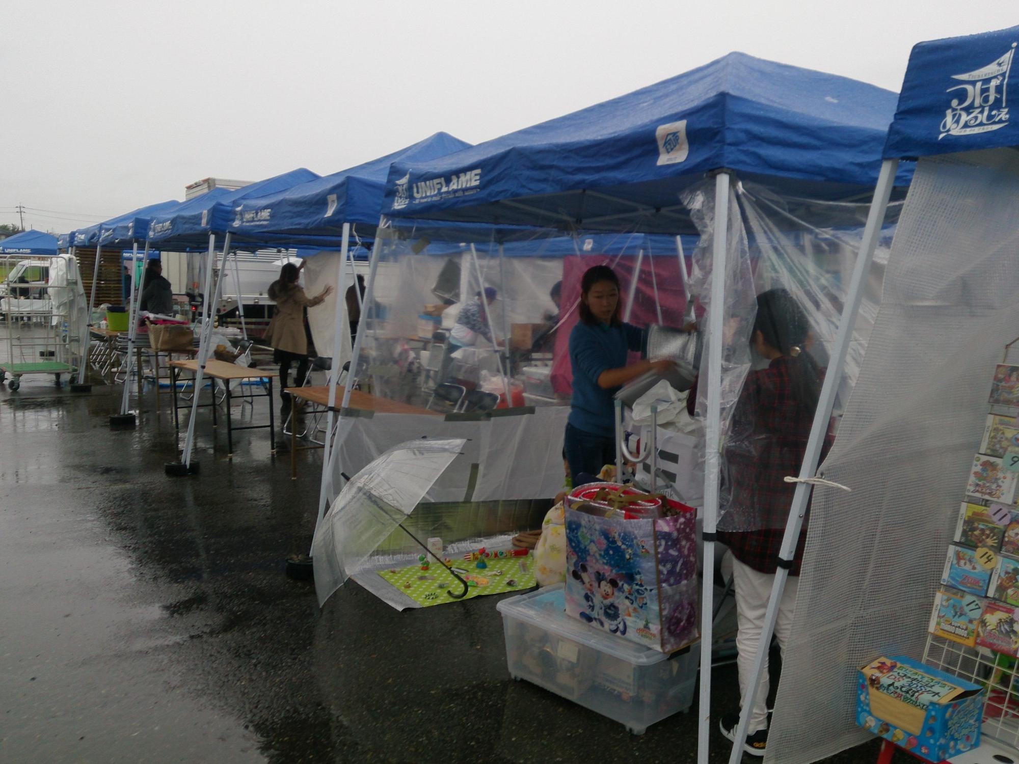 雨空の下青いパラソルの出店で開催されたフェスの写真