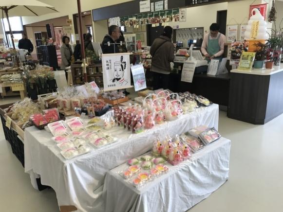 土産物売場にて、白い布を敷かれた机の上で販売されている天神講菓子の様子を写した写真
