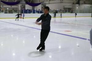 リンクの上で足を組むようにスケートする男性の写真
