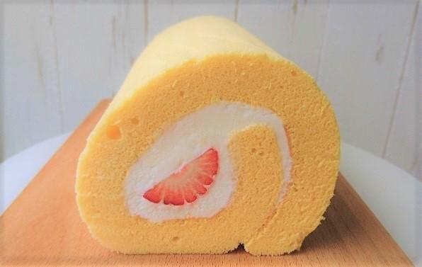 オレンジ色のロールケーキに白いクリームとイチゴが入っている写真