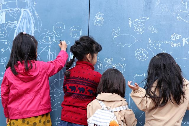 4人の女の子たちが集まって壁面アートを描いている写真