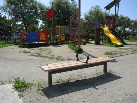 カラフルな遊具が並ぶみなみ親水公園に設置されたベンチの写真