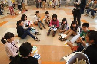 A、B、Cの札を持った子どもたちが床に座って説明を聞いている写真