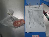ポリ袋に入った50グラムの肉の横に、バインダーに綴じられた用紙とペンが置かれている写真