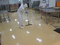 調理室の床をワイパーを使って清掃している作業者の写真
