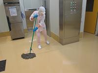 調理室の床をモップを使って消毒している作業者の写真