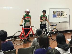 自転車を並べて説明している部活動の生徒と、説明を聞いている参加者の写真