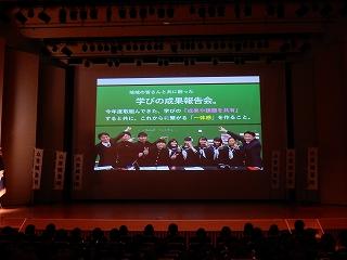 壇上のスクリーンに表示された、「学びの成果報告会」のスライドの写真