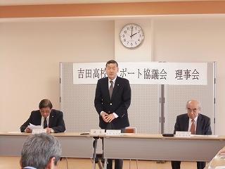 「吉田高校サポート協議会 理事会」の表示の前で、立って話をしている男性と、隣に座っている男性二人の写真
