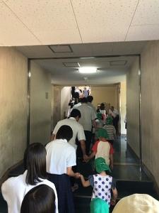園児たちと手をつないだ生徒たちが、列になって廊下を歩いている写真