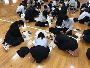 床に座り、紙に書き込むなどのグループワークを行っている生徒たちの写真
