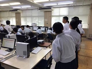 パソコン室で作業をしている生徒たちと、その様子を並んで見学している生徒たちの写真