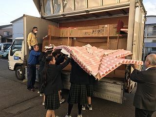 トラックに模型の一部を積み込んでいる生徒たちと職員の写真
