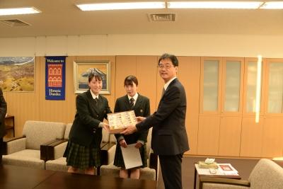2人の女子生徒が箱に詰められた和菓子を手渡している様子の写真