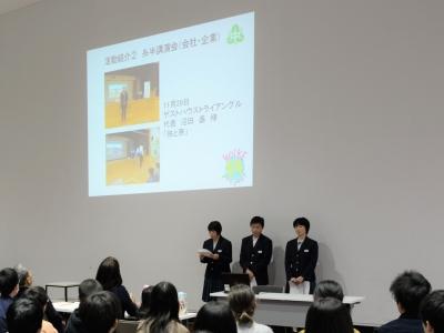 映像の写ったスクリーンの前で発表をする3人の制服を着た中学生の写真