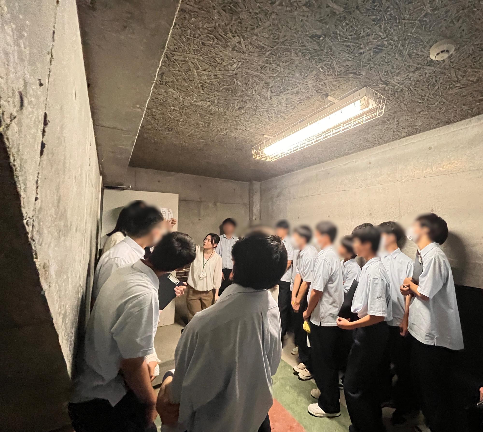 分水高校生が地下にて職員からの説明を聞いている写真。