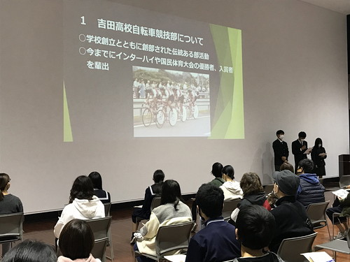 吉田高校の自転車競技部の部員が部活紹介のスライドを説明している写真