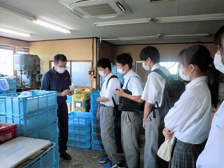 社長が製品を手に持って、生徒5人に対してその製品の説明をしている写真。