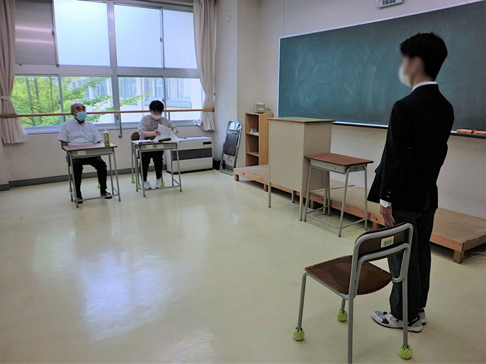 面子の開始時、男子生徒が入室して、椅子に座る前に、2人の面接官に礼をしているところ。
