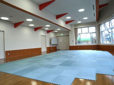 木目の床に水色のクッションカーペットが敷かれている研修室の様子