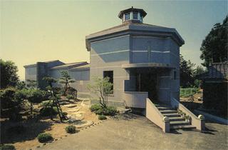 青い空と整備された植え込みに囲われた長善館の外観写真