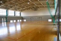 地面にラインが引かれており壁には緑色のネットがある体育センター内部の写真