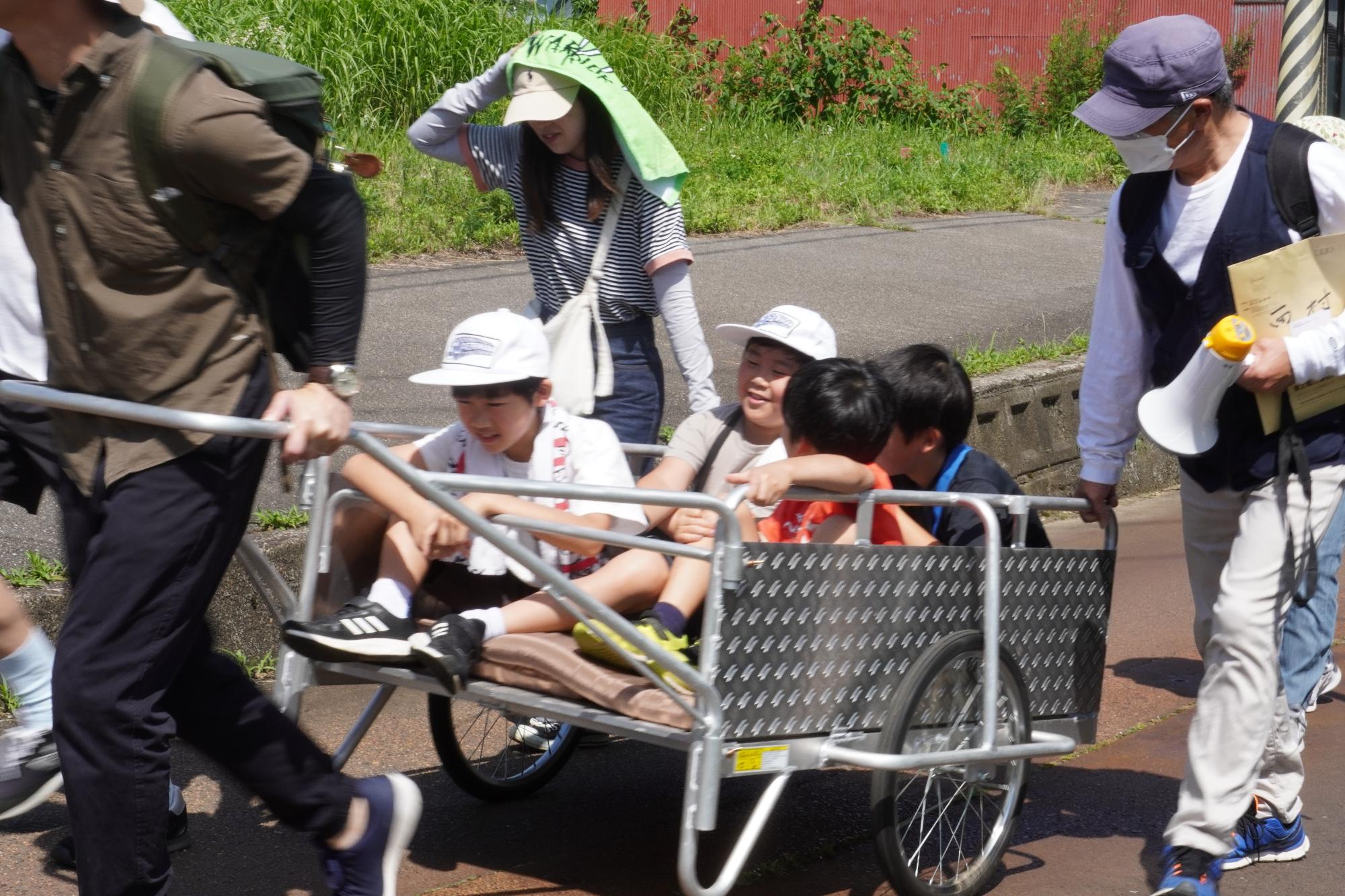 要支援者役をした小学生達の乗るリアカーを曳く地域住民
