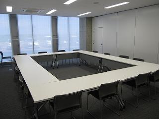 椅子と白い机が並べられた部屋の写真