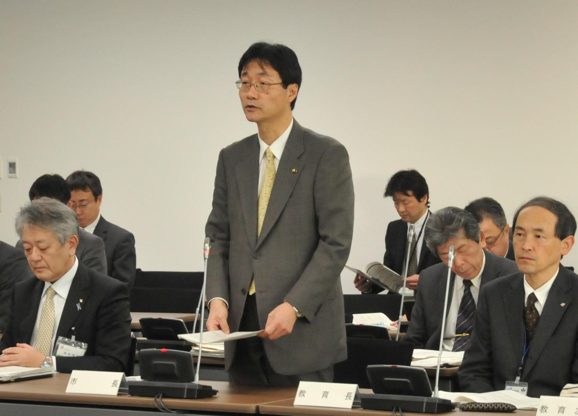 スーツ姿で起立し話をする鈴木市長の写真