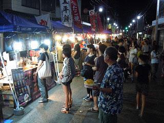 ライトアップされた屋台でかき氷やたこ焼きが並ぶ写真