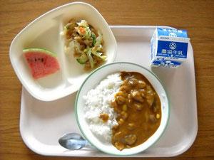 カレーライス、スイカ、野菜炒めなどが並んだ給食の写真