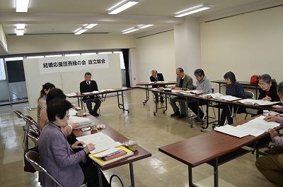 机を並べて資料を見ながら会議を行う人たちの写真