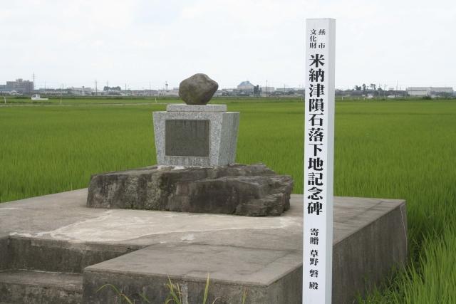 緑の田んぼの中に立つ記念碑の写真
