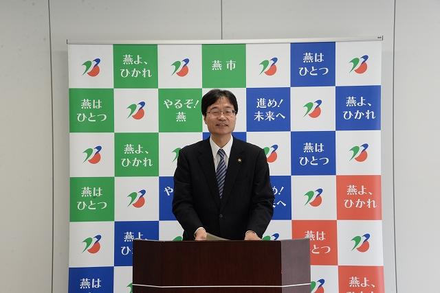 スーツ姿で演台に立ち発表をする市長の写真