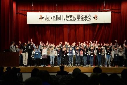 ステージの上で子供たちが両手を挙げている写真
