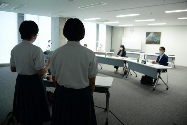 資料を見ながら発表している二人の女子生徒の後ろ姿と、座って聞いている人たちの写真