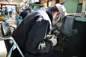 磨き屋一番館の機械で金属を加工する男性の写真