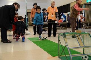 小さなサッカーゴールに向けて小さなサッカーボールを蹴ろうとする男の子の写真