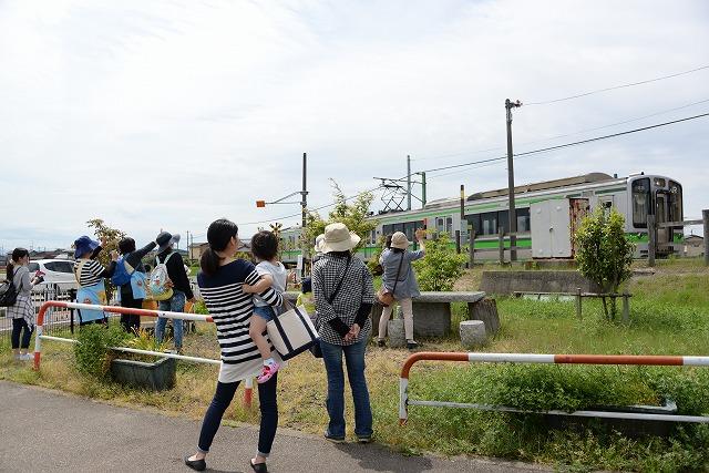 入ってくる弥彦方面に向かう電車と駅で手を振って見送る保護者と子供達の写真